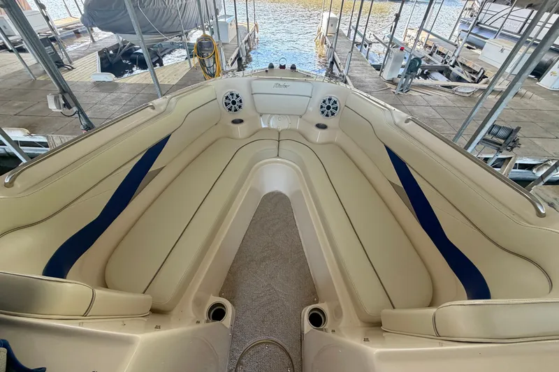 Slide: The Image of 2005 Rinker 282 Captiva Bowrider interior with beige seating and blue accents at a dock. - 17