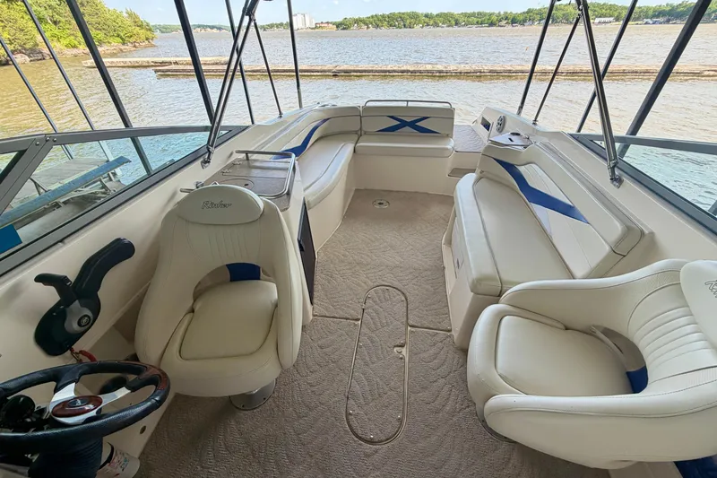 Slide: The Image of 2005 Rinker 282 Captiva Bowrider interior with white seating, steering wheel, and lake view. - 21