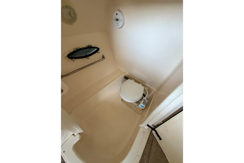 Slide: The Image of 2005 Rinker 282 Captiva Bowrider boat bathroom with toilet and porthole window. - 23