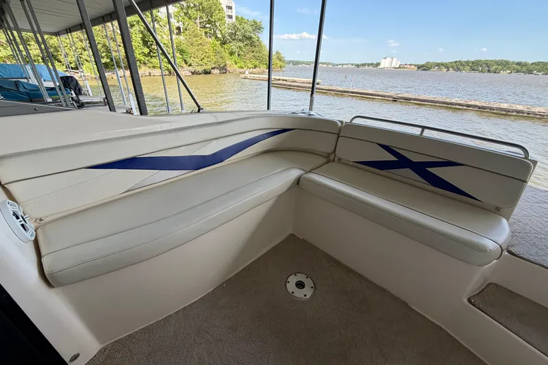 Slide: The Image of 2005 Rinker 282 Captiva Bowrider interior with blue accents, docked by a scenic lake. - 7