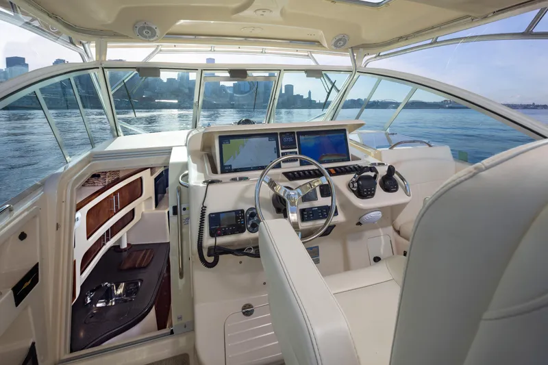 Slide: The Image of 2006 Grady-White Express 360 helm with navigation screens, overlooking calm waters and city skyline. - 16
