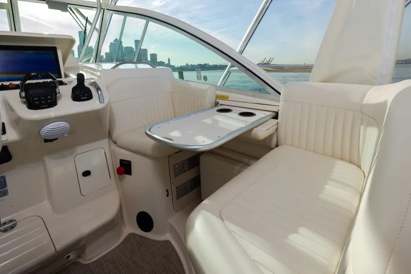 Slide: The Image of 2006 Grady-White Express 360 boat interior with helm, seating, and table, overlooking city skyline. - 19