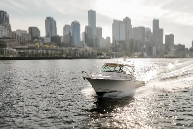 Slide: The Image of 2006 Grady-White Express 360 boat cruising on water with city skyline backdrop. - 9