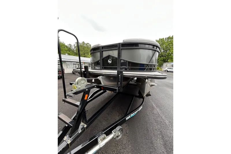 Slide: The Image of 2025 South Bay 525 Tritoon on trailer, parked outdoors, showcasing front view and sturdy design. - 51