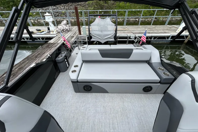 Slide: The Image of 2025 South Bay 525UL393 pontoon boat interior with gray seating and cup holders at dock. - 26