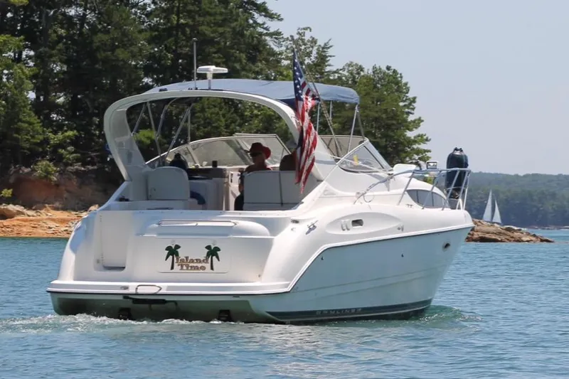 Slide: The Image of 2002 Bayliner 3055 Ciera cruising on a serene lake with lush green trees. - 3