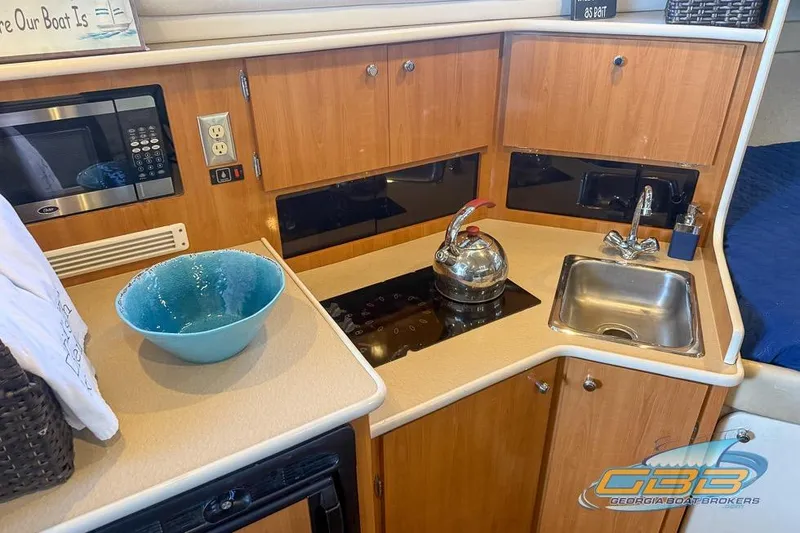Slide: The Image of 2002 Bayliner 3055 Ciera kitchen with sink, stove, microwave, and blue bowl. - 6