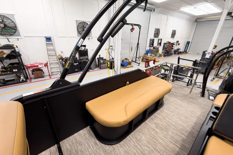 Slide: The Image of 2026 Godfrey Sweetwater 22' Tritoon interior with tan seating in a workshop setting. - 19