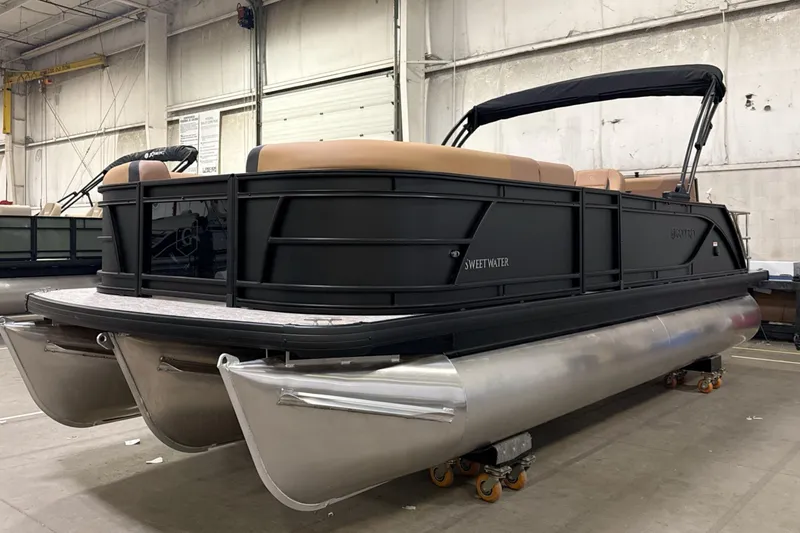 Slide: The Image of 2026 Godfrey Sweetwater 22' Tritoon boat in warehouse, featuring sleek black design. - 32