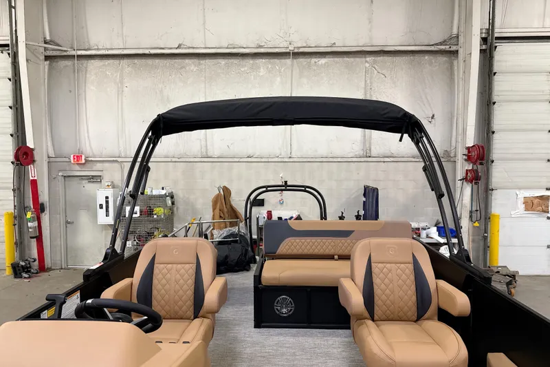 Slide: The Image of 2026 Godfrey Sweetwater 22' Tritoon interior with tan seating in a warehouse setting. - 37