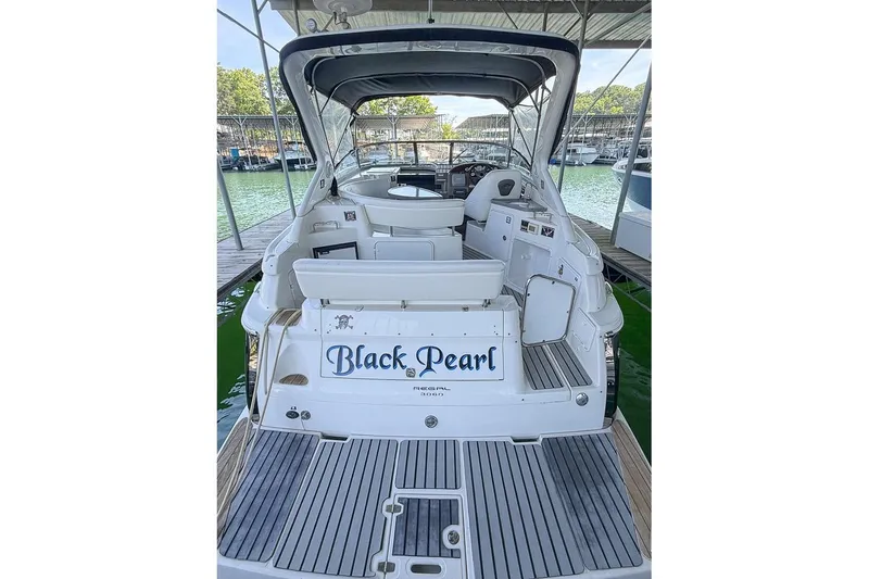 Slide: The Image of 2006 Regal 3060 Window Express boat docked, named "Black Pearl," with spacious seating area. - 30