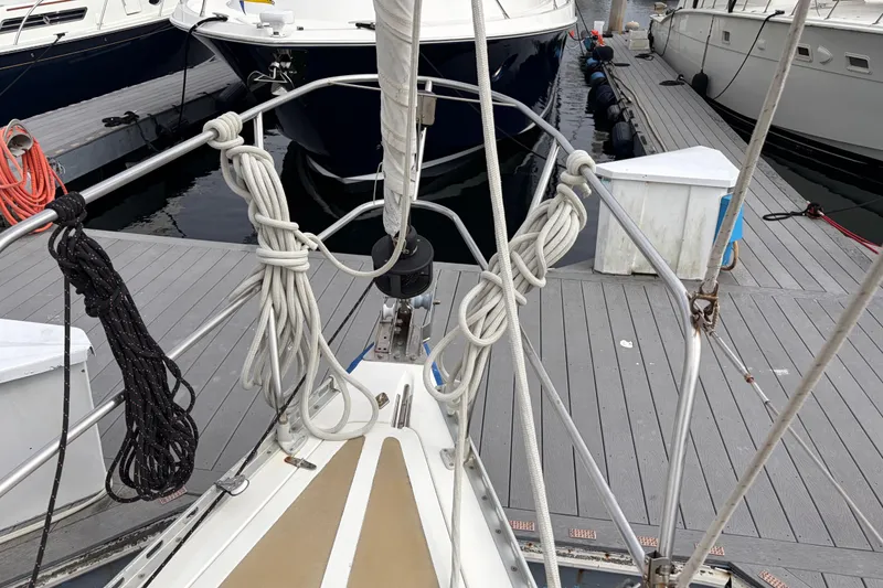 Slide: The Image of Bow of a 1986 Nordic 44 sailboat docked, with neatly coiled ropes and adjacent vessels. - 14