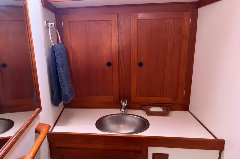 Slide: The Image of Wooden bathroom vanity with sink, towel, and mirror on a 1986 Nordic 44 boat. - 33