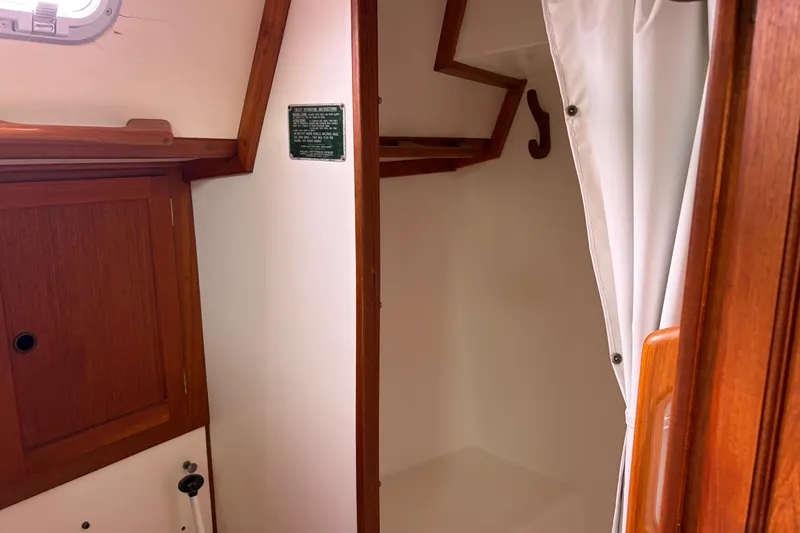 Slide: The Image of Interior of 1986 Nordic 44 sailboat with wooden cabinetry and white curtain. - 35