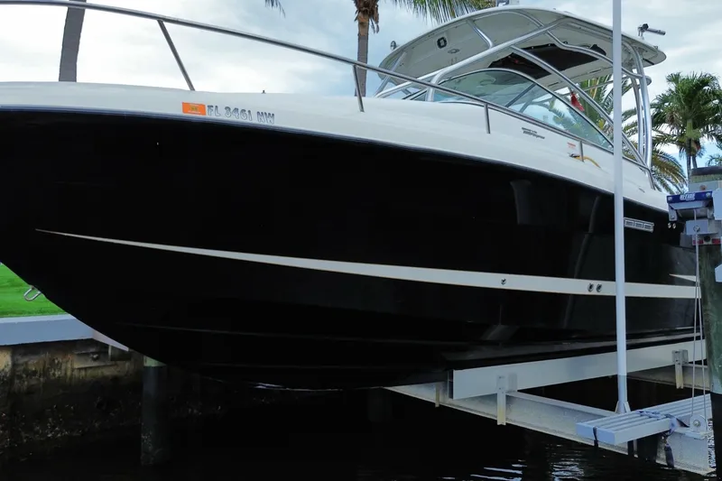 Slide: The Image of 2006 Hydra-Sports Vector 2900 VX boat on lift, sleek black hull, palm trees in background. - 5