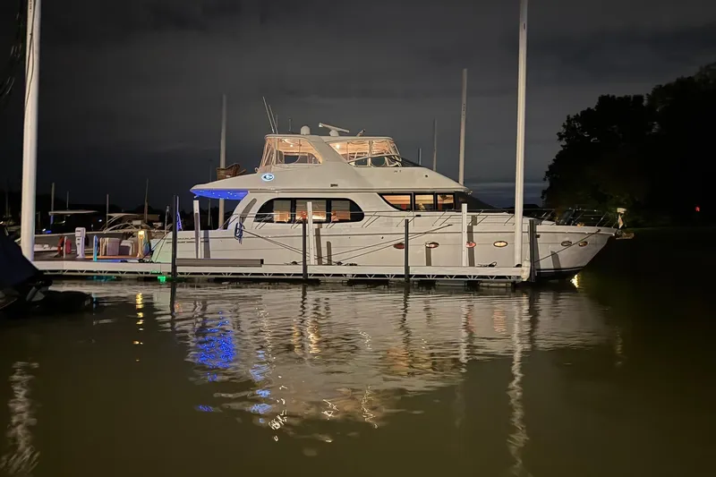Slide: The Image of 2006 Carver 56 Voyager yacht docked at night, reflecting on calm water. - 2