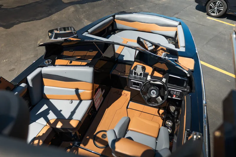 Slide: The Image of 2025 Axis A225 boat interior with tan and gray seating, steering wheel, and dashboard. - 13