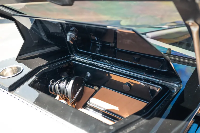 Slide: The Image of Open storage compartment in 2025 Axis A225 boat, featuring coiled cable and cup holder. - 32