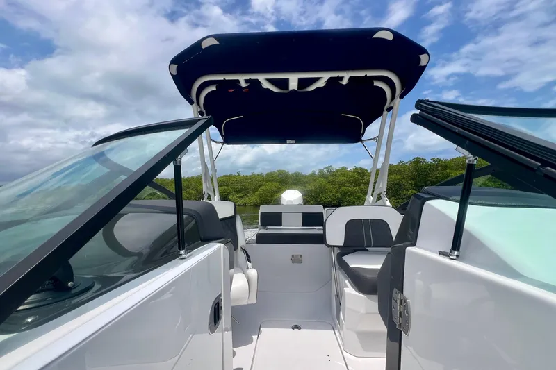 Slide: The Image of 2024 Monterey M-45 boat interior with canopy, open seating, and lush greenery background. - 13