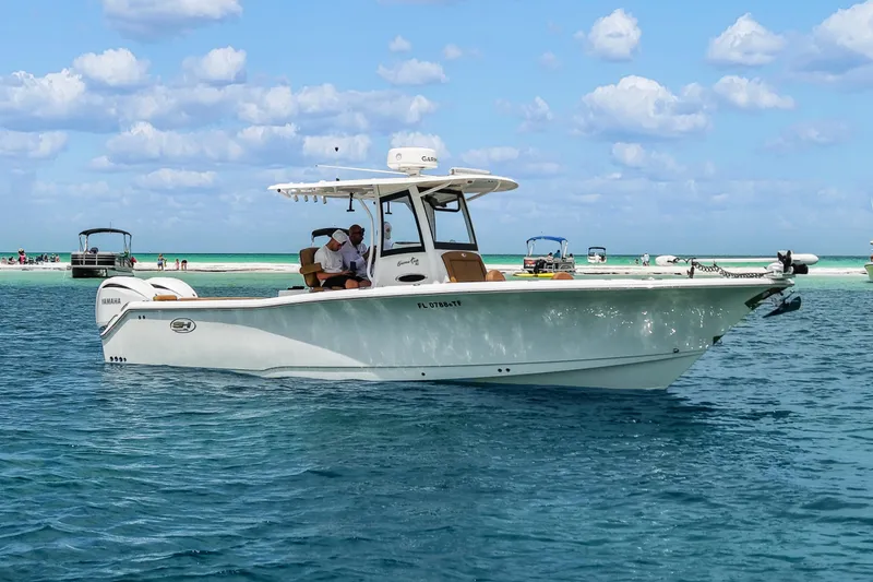 The Image of 2022 Sea Hunt Gamefish 30 boat on clear blue water, sandy beach in background. - 0