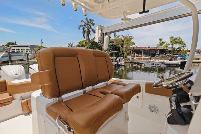 Slide: The Image of 2022 Sea Hunt Gamefish 30 boat with brown seating and steering wheel, docked near waterfront homes. - 34