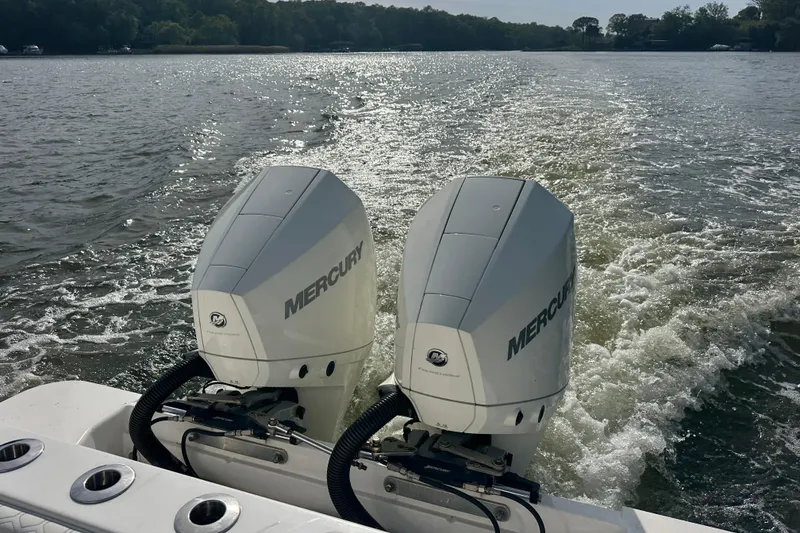 Slide: The Image of Twin Mercury outboard engines on a 2020 Belzona 27 CC boat cruising on a sunny lake. - 12