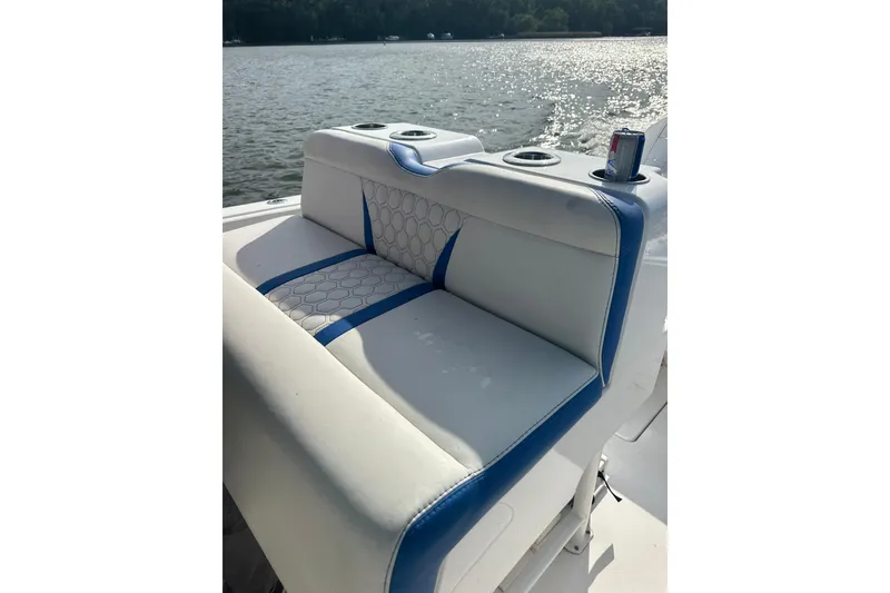Slide: The Image of White and blue seating on a 2020 Belzona 27 CC boat, with cup holders and lake view. - 16