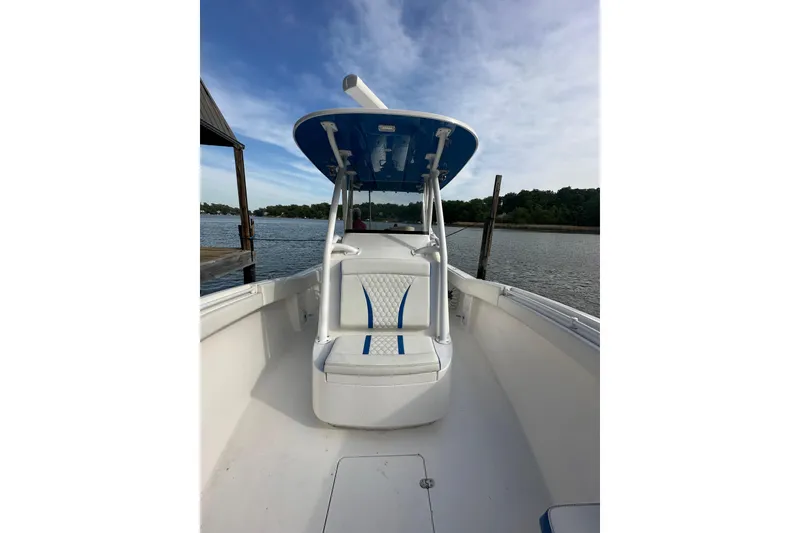 Slide: The Image of 2020 Belzona 27 CC boat with blue accents, docked on a calm lake. - 26