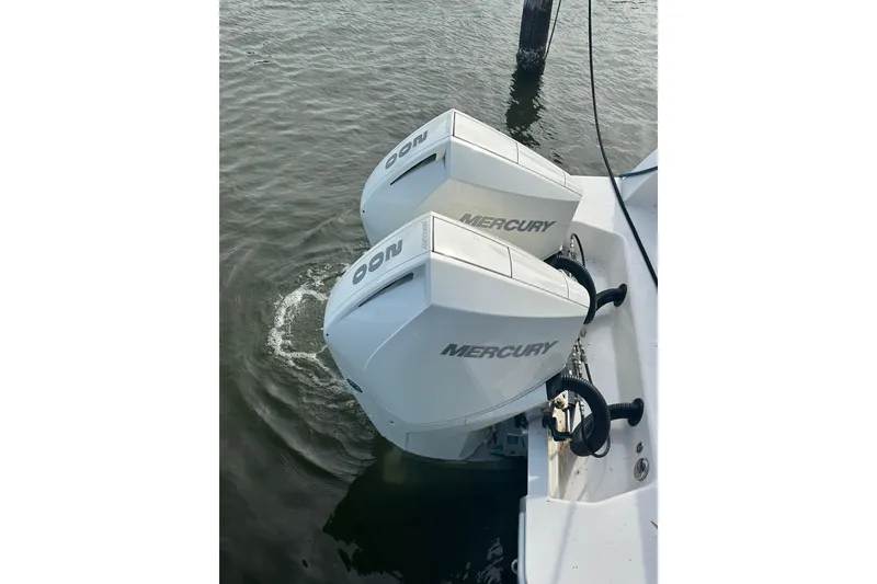 Slide: The Image of Twin Mercury outboard engines on a 2020 Belzona 27 CC boat in water. - 11