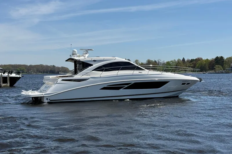 Slide: The Image of 2014 Sea Ray Sundancer 510 yacht cruising on a calm lake under a clear blue sky. - 2