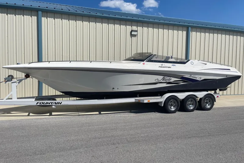 The Image of 1998 Fountain 29 Fever speedboat on trailer, parked outside a metal building. - 0