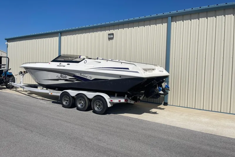Slide: The Image of 1998 Fountain 29 Fever boat on trailer beside metal building. - 2