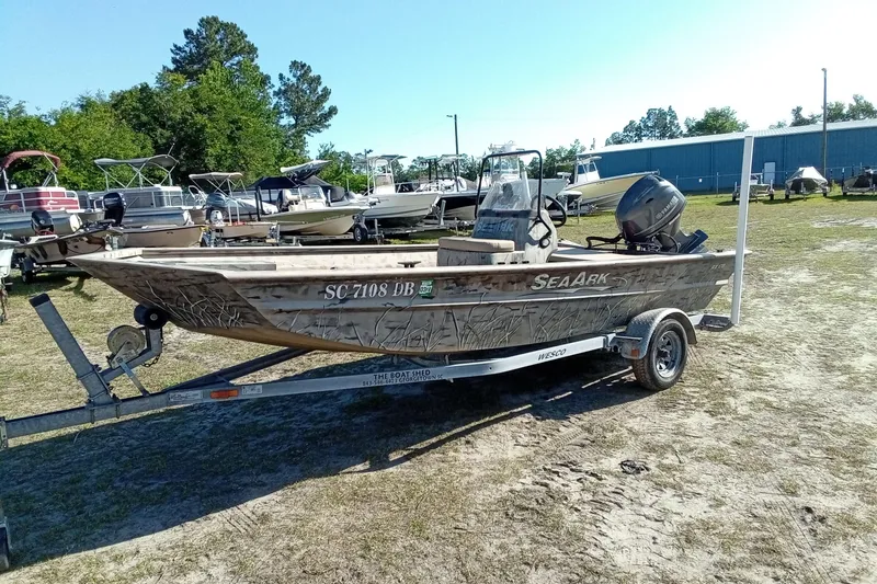 Slide: The Image of 2015 SeaArk 170 RX boat on trailer, parked outdoors with other boats. - 6