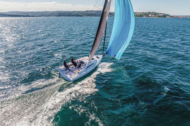Slide: The Image of 2026 Beneteau First 30 sailboat gliding on open water with blue spinnaker sail. - 3