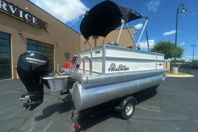Slide: The Image of 2026 Sun Tracker Party Barge 16 DLX pontoon boat with Mercury engine, parked outdoors. - 1