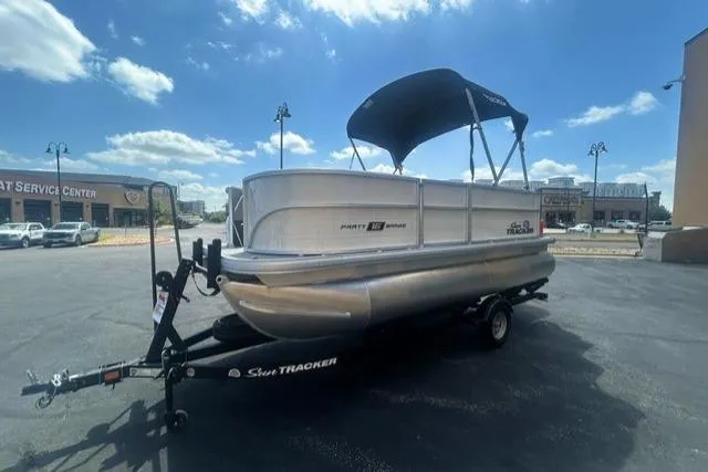 Slide: The Image of 2026 Sun Tracker Party Barge 16 DLX pontoon boat on trailer under blue sky. - 2