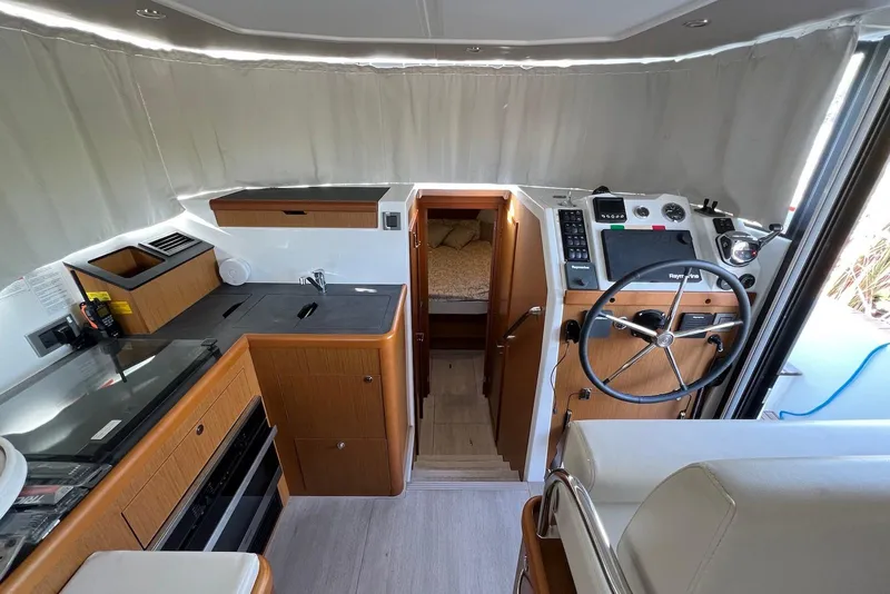 Slide: The Image of Interior of 2020 Beneteau Swift Trawler 35, featuring helm, kitchen, and cabin entrance. - 8
