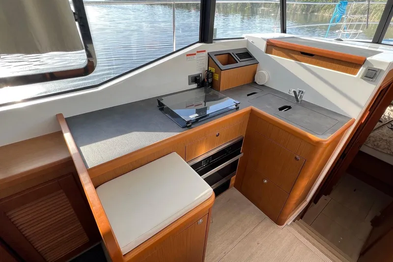 Slide: The Image of 2020 Beneteau Swift Trawler 35 kitchen area with modern appliances and wood cabinetry. - 12