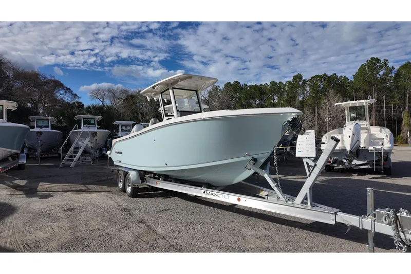 Slide: The Image of 2026 Sailfish 252 CC boat on trailer, parked outdoors under a partly cloudy sky. - 2