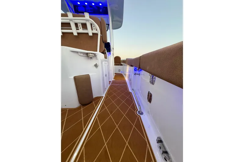 Slide: The Image of 2024 Sea Hunt Ultra 265 SE boat deck with brown flooring and blue LED lights. - 19