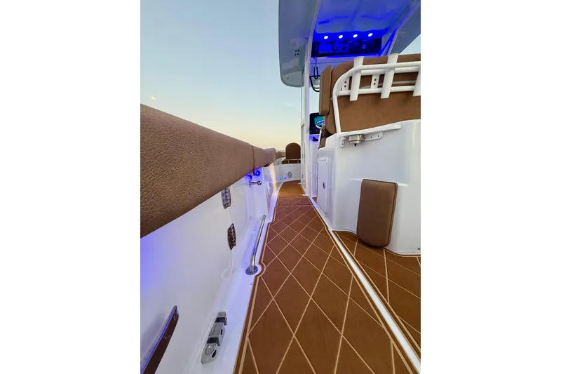 Slide: The Image of 2024 Sea Hunt Ultra 265 SE boat interior with brown cushioned seating and ambient blue lighting. - 22