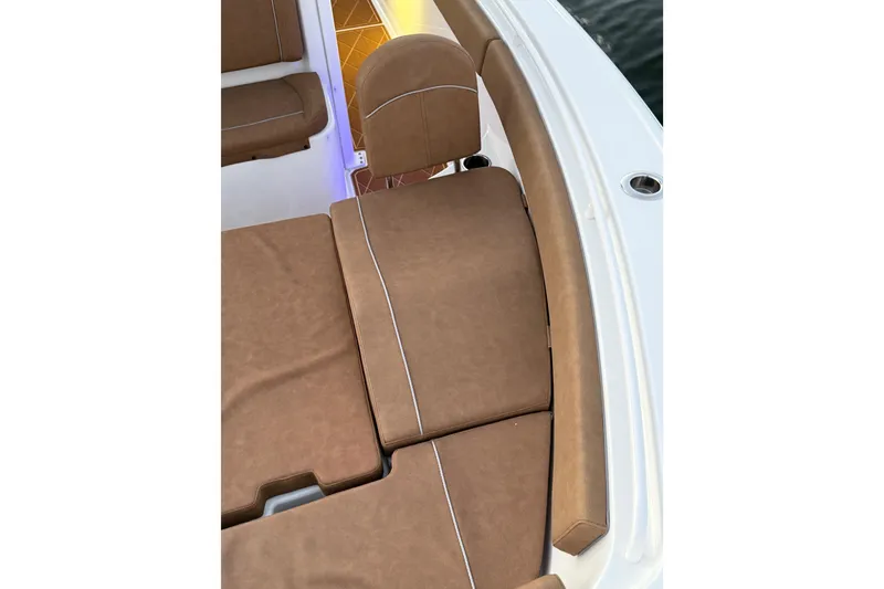 Slide: The Image of 2024 Sea Hunt Ultra 265 SE boat with brown cushioned seating and ambient lighting. - 32