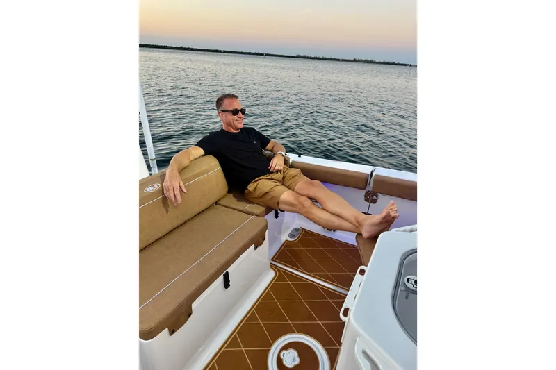 Slide: The Image of Man relaxing on a 2024 Sea Hunt Ultra 265 SE boat at sunset. - 46