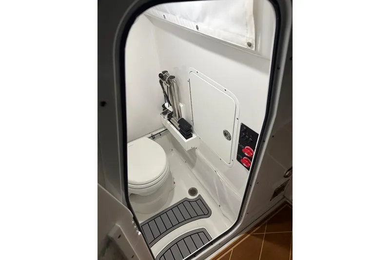 Slide: The Image of 2024 Sea Hunt Ultra 265 SE boat interior bathroom with toilet and storage. - 48