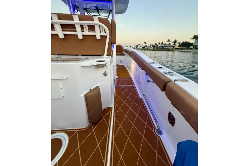 Slide: The Image of 2024 Sea Hunt Ultra 265 SE boat interior with brown seating and deck, near water. - 6