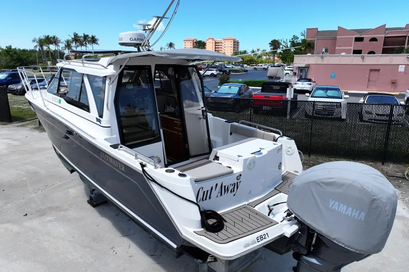 Slide: The Image of 2022 Cutwater C-248 Coupe boat with Yamaha engine, parked outdoors near buildings and cars. - 2