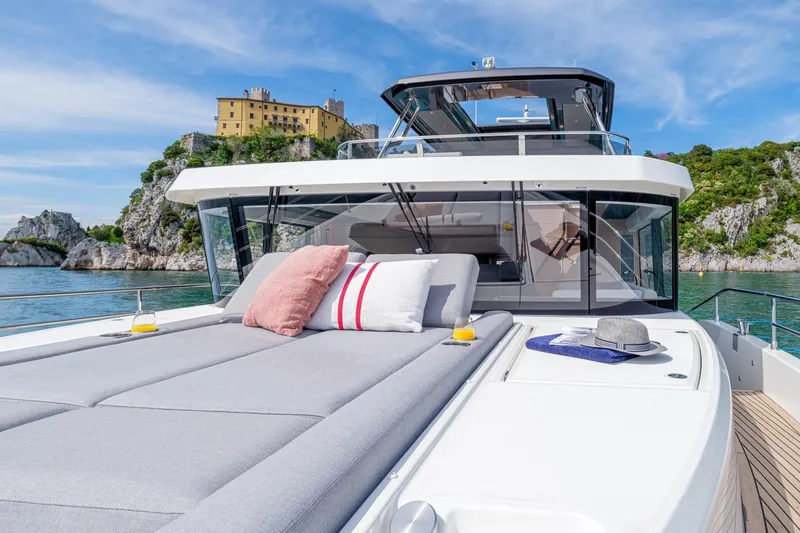 Slide: The Image of Luxurious 2022 Beneteau Grand Trawler 62 yacht with sunbathing area, scenic coastal backdrop. - 7