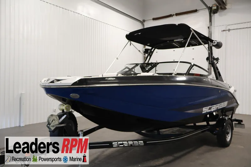 The Image of 2021 Scarab 215 ID boat in showroom, blue exterior, on trailer. - 0