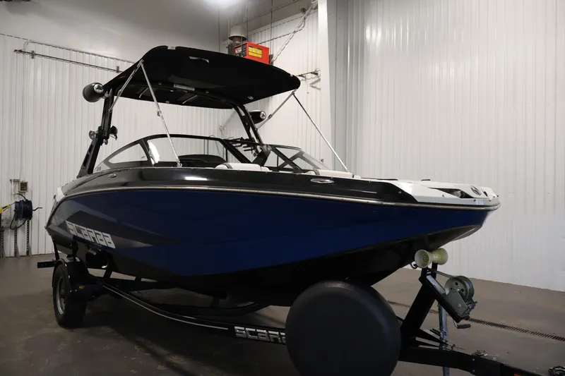 Slide: The Image of 2021 Scarab 215 ID boat in a garage, featuring a sleek blue and black design. - 2