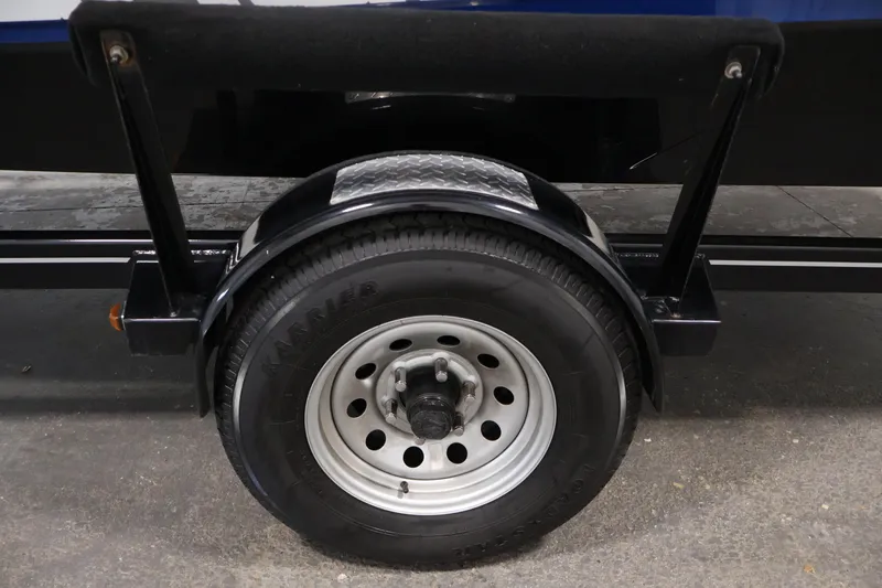 Slide: The Image of Trailer wheel of a 2021 Scarab 215 ID boat, featuring a sturdy tire and metal fender. - 47